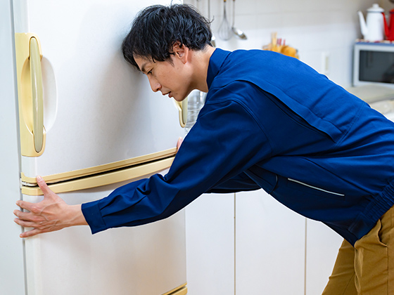 男性スタッフが冷蔵庫をもち運びだそうとする画像